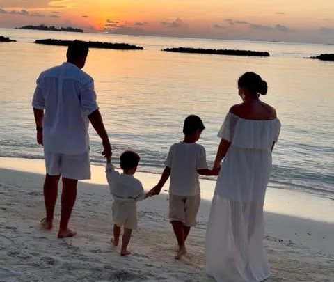 Bella and her family walking along the beach at sunset