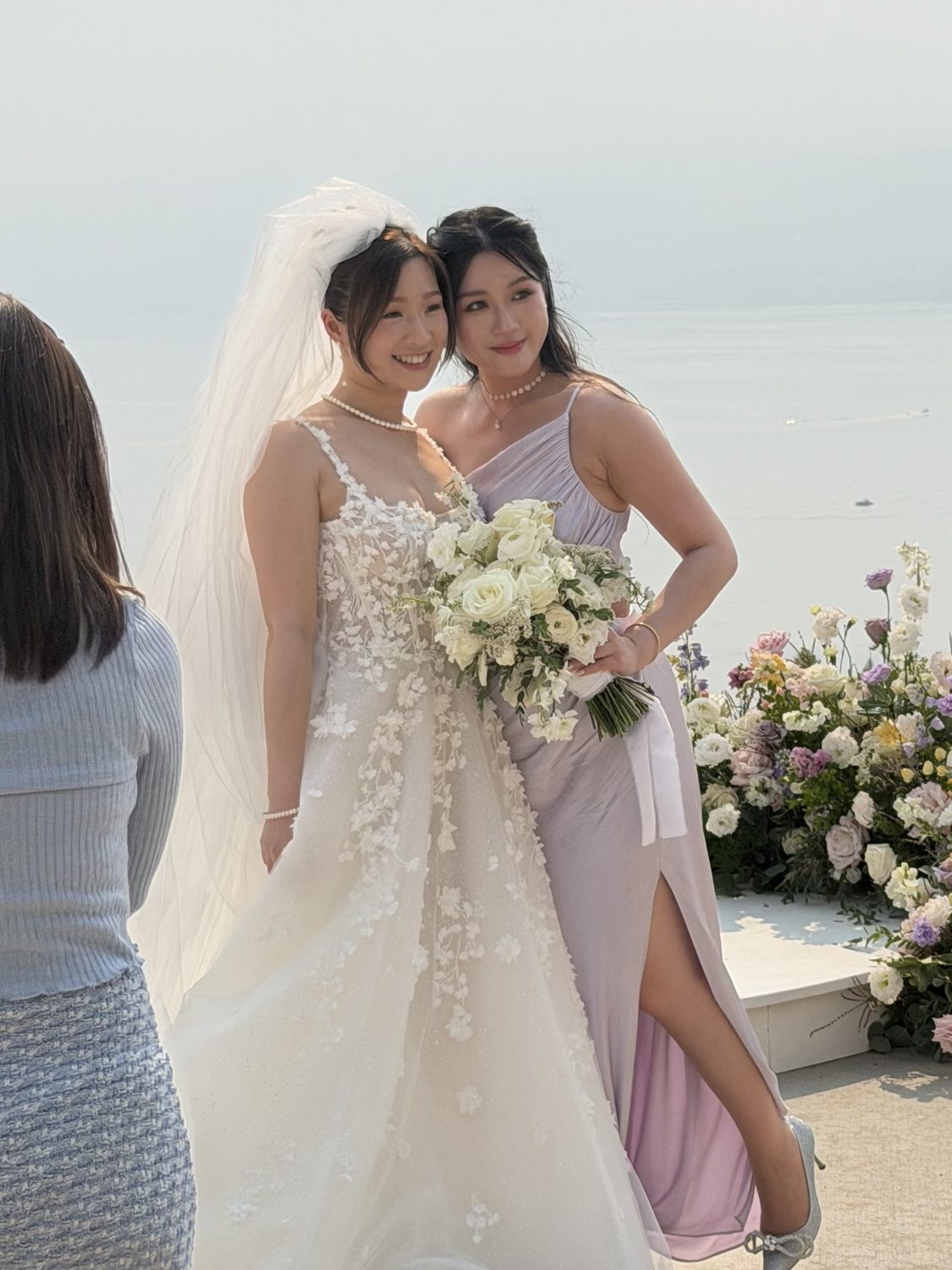 Two brides with bouquets by the water