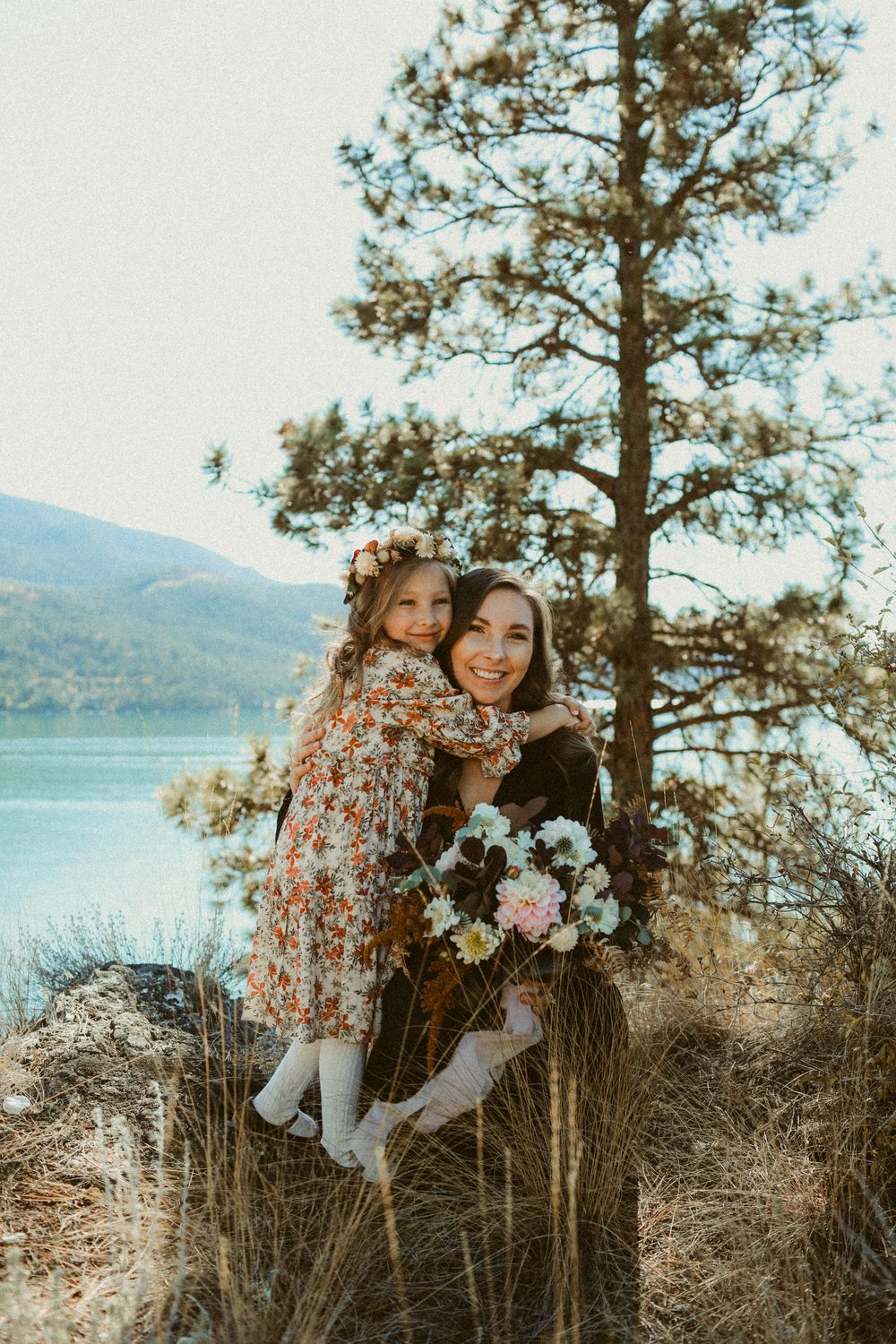 Mother and daughter by a pine above the lake